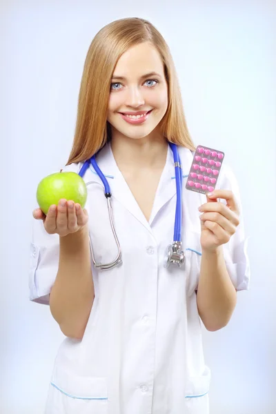 Nurse holding an apple and pills