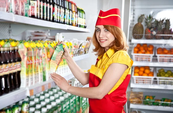 Female the seller in the supermarket holding a box of juice