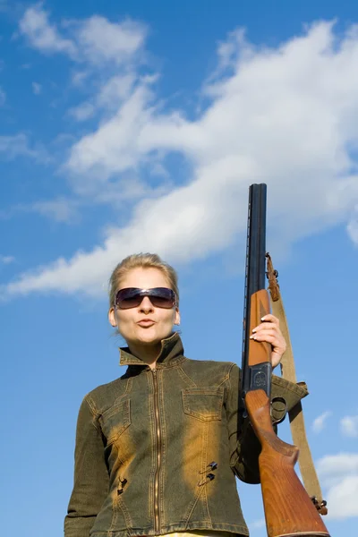 Blonde girl in sunglasses holding hunter rifle.