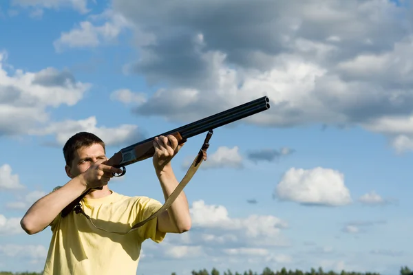 Caucasian man aiming. Cloudy sky background.