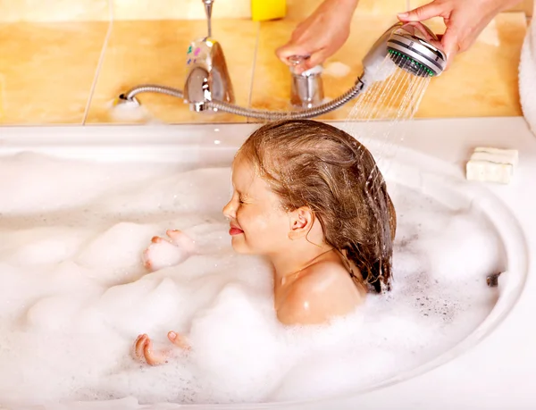 Child washing hair in bubble bath.