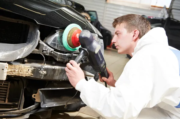 Mechanic repairing and polishing car headlight