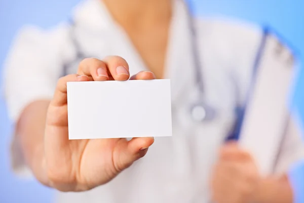 Doctor (woman) holding blank business card with copy space on bl