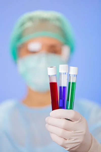 Medical test tube samples in doctor's hand on blue background