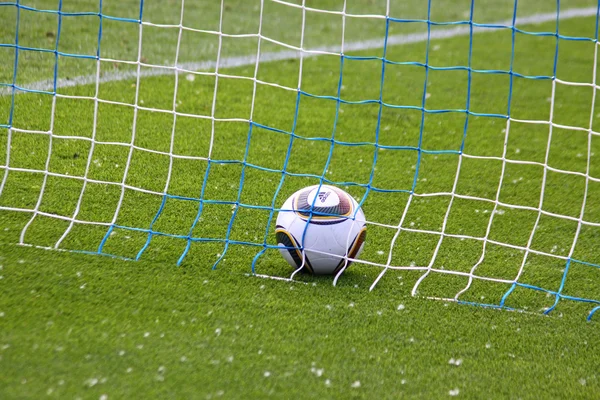 Soccer ball inside the net on the green grass field