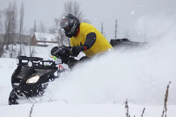 The quad bike\'s driver rides over snow track