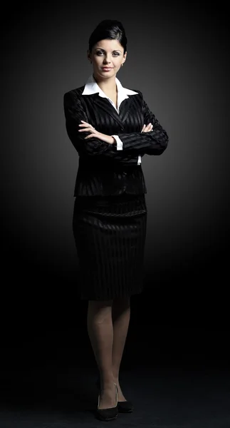 Confident business woman standing full length in black suit