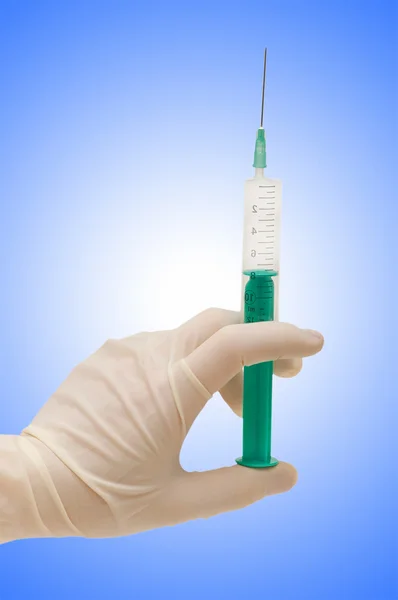 Hand holding syringe on gradient
