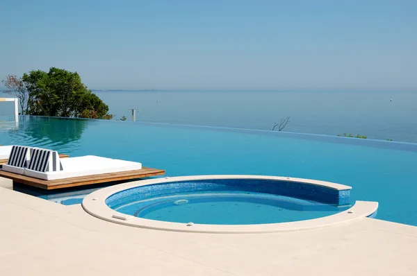 Infinity swimming pool with jacuzzi by beach at the modern luxu