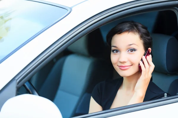 Pretty asian girl in a car talking by mobile telephone