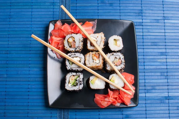 Sushi on a black plate on table.