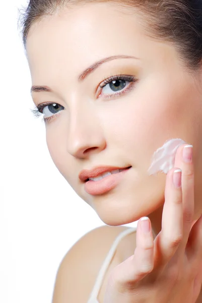 Beautiful woman applying cream on face
