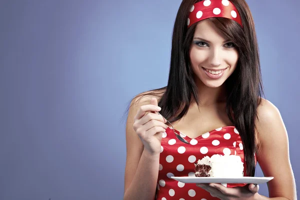 The beautiful young woman eat a slice of a sweet cake