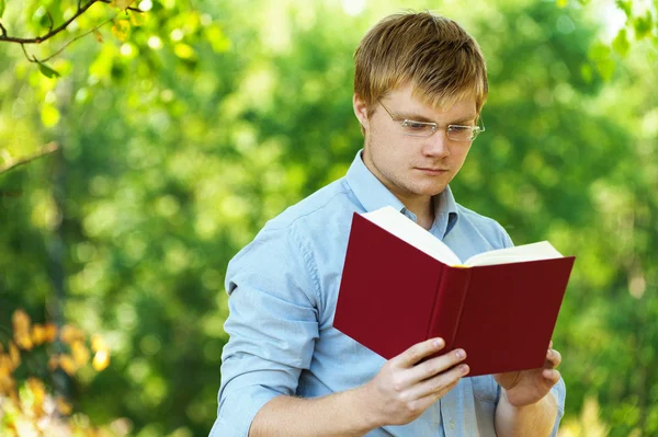 Student (male) with glasses reading book