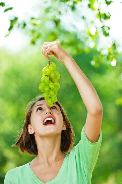 Portrait of woman with bunch of green grapes
