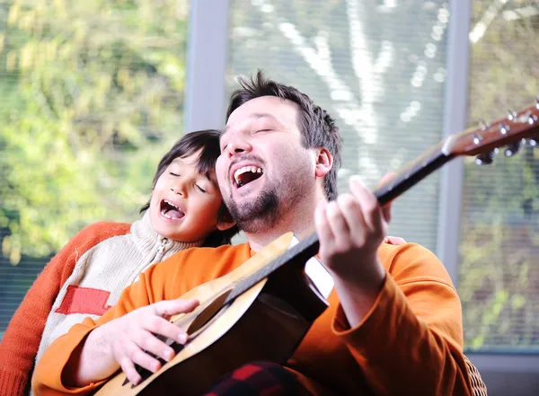 Father and son playing guitar at home