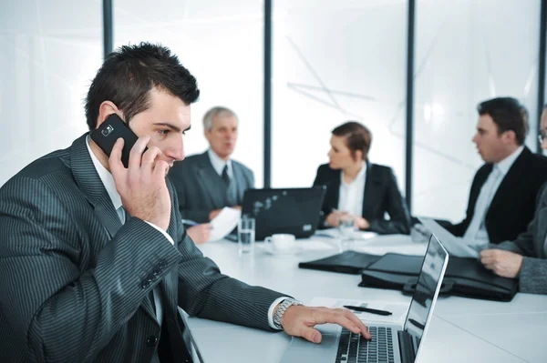 Business man speaking on the phone while in a meeting