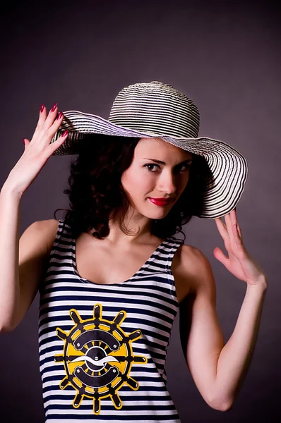 Beautiful young woman in hat on dark background