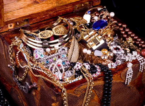 Old wooden open chest with golden jewelry