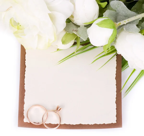 Gold wedding rings on a bouquet of white roses with banner add