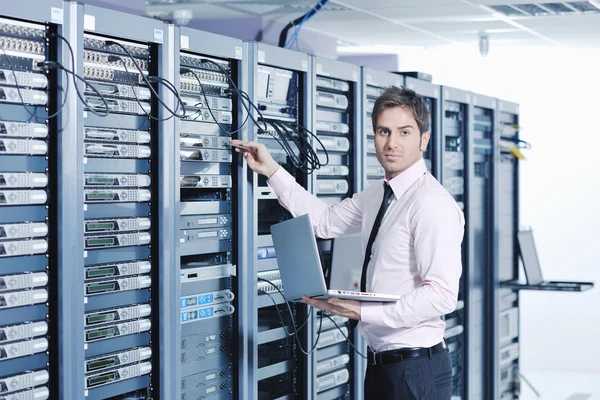 Businessman with laptop in network server room