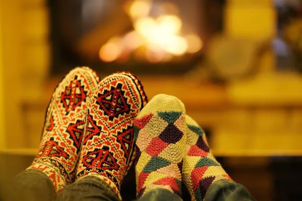 Young romantic couple sitting on sofa in front of fireplace at home