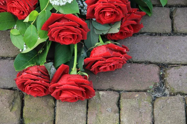 Red rose sympathy flower arrangement on pavement