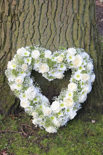 Heart shaped sympathy arrangement near a tree