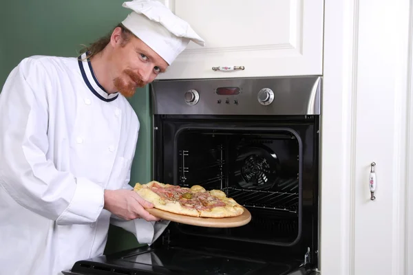Young chef with italian pizza in kitchen