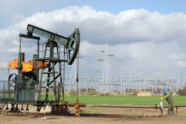 Oil field with pumpjack and oil worker