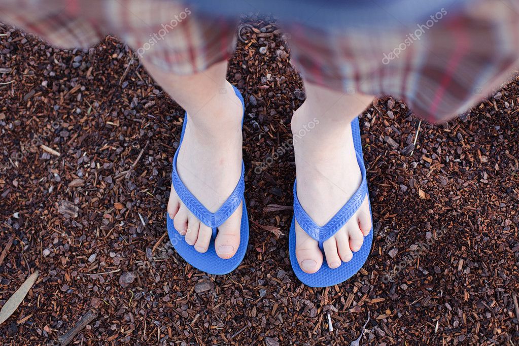 Woman bare sandy feet with blue flip flops, beach and sea Stock