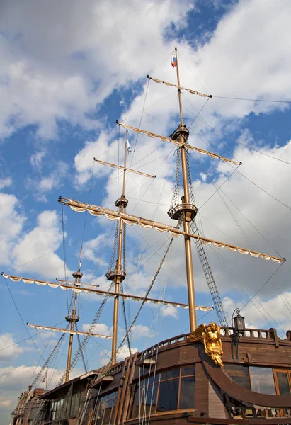 The mast is an old wooden ship against the blue sky