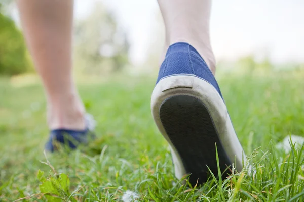Walking on green grass in sport shoes