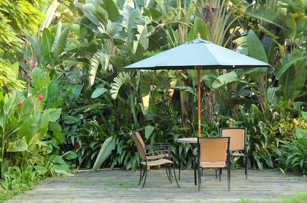 Garden furniture - rattan chairs and table under umbrella on a w