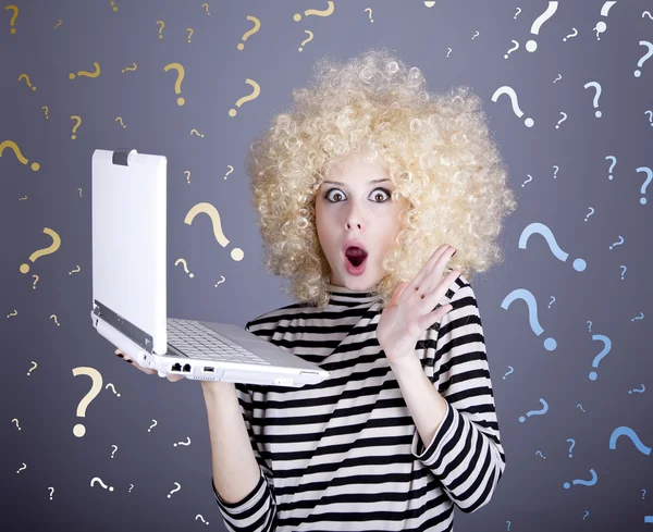 Portrait of surprised girl in blonde wig with laptop and questions.
