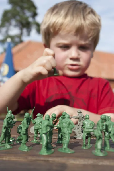 Young child playing soldiers and armies outside in the summer