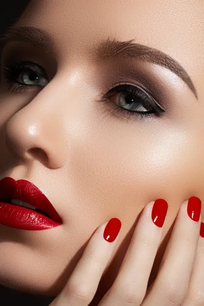 Beautiful close-up portrait of fashion woman model with glamour classic makeup, red lipstick, bright nail polish. Evening style, retro visage and manicure