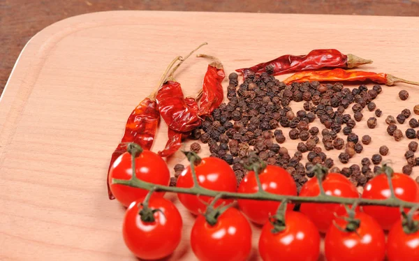 Black pepper red pepper and tomato on the wooden cutting board