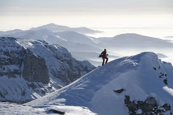Man climbing a peak with snowboard