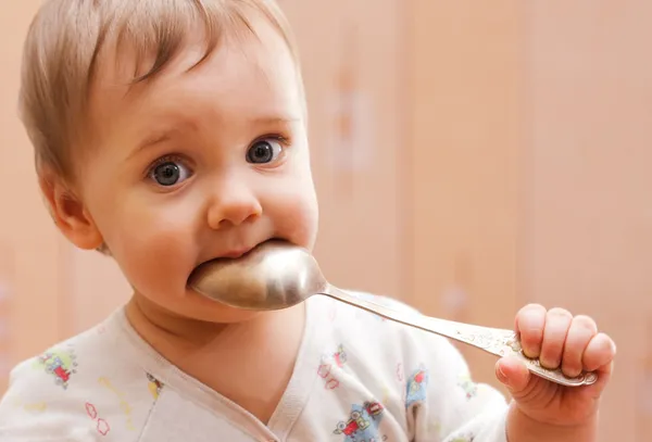 Baby girl holding spoon in mouth