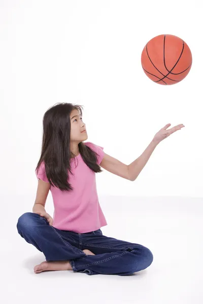 Ten year old Asian girl holding basketball, isolated on white