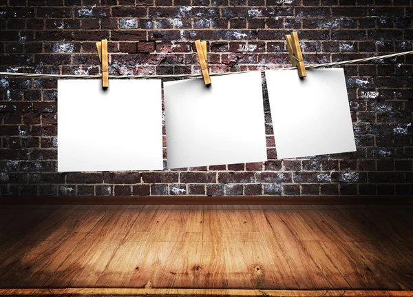 White papers attach to rope with clothes pins on brick wall background