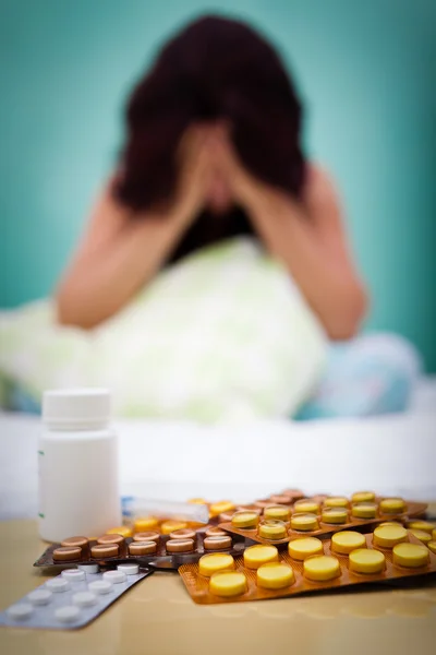 Pills and out of focus sick or depressed woman