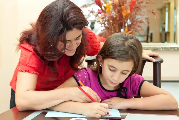 Latin mother helping her daughter with her school art project