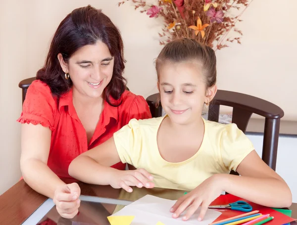 Latin mother helping her daughter with her school art project