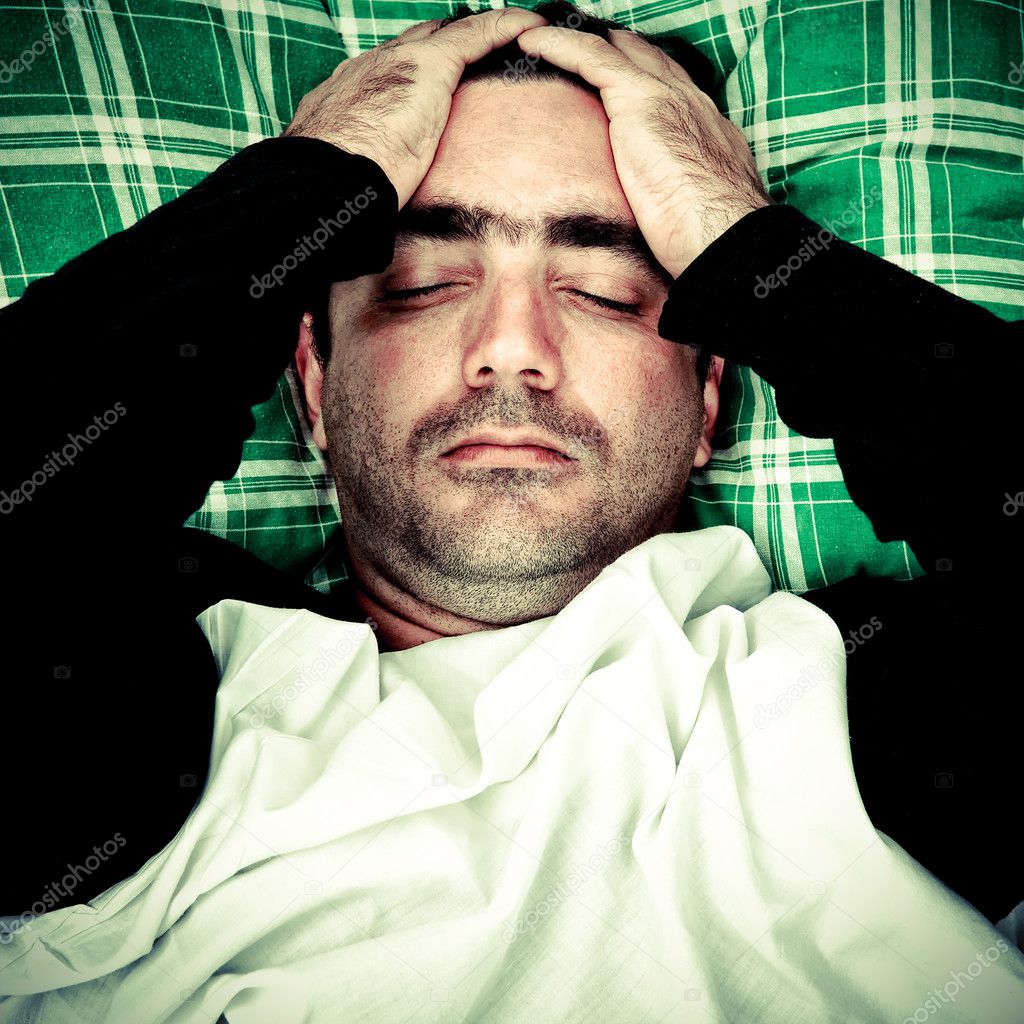 stressed-or-mentally-disturbed-man-laying-in-bed-stock-photo