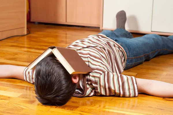 Teenage boy fell asleep while reading on the floor