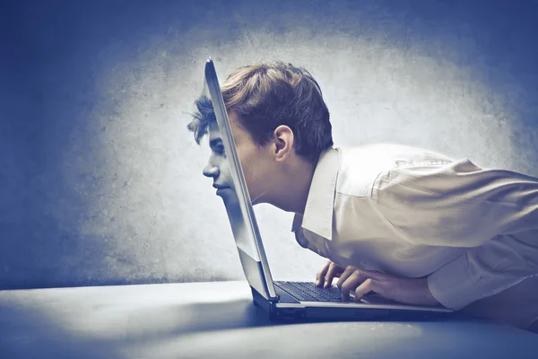 Young businessman with his face passing through the screen of a laptop