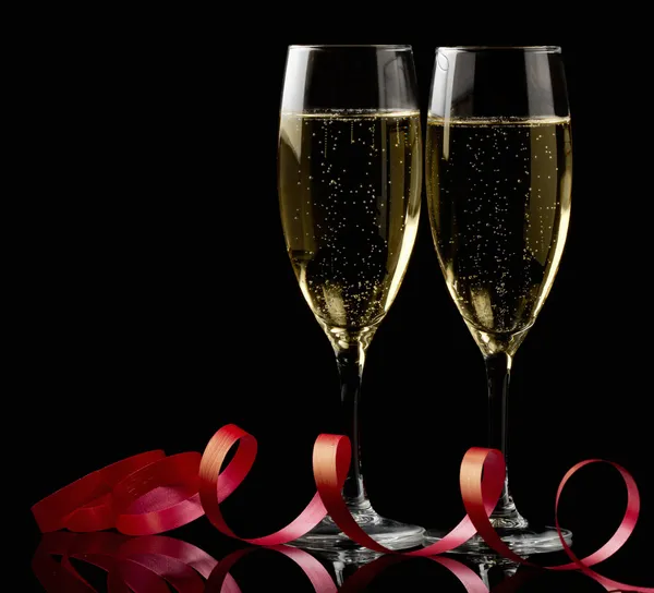 Two glasses with white wine over black background with red ribbon