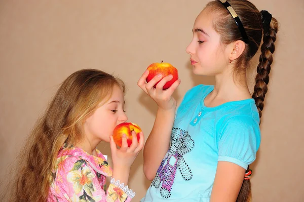 Two girls eat apples